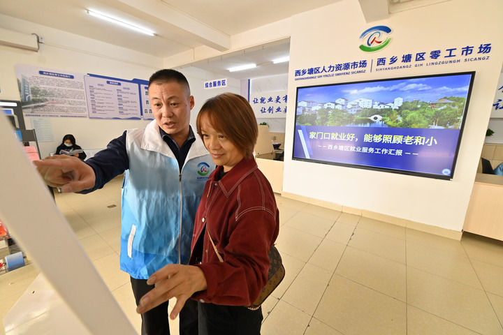 在广西南宁市西乡塘区零工市场,工作人员(左)指导市民查找就业招聘信息(2025年12月10日摄)。新华社记者 陆波岸 摄