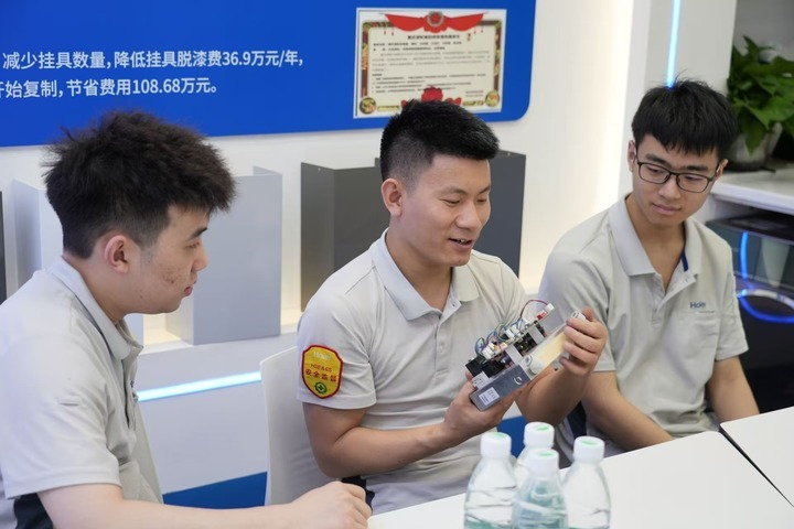 2025年5月，全国政协委员卢跃富（中）在他的劳模工作室与同事交流。