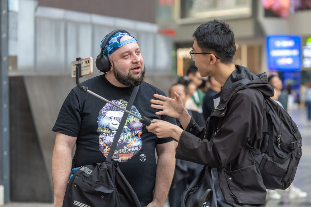 ↑ 4月22日，在重庆市渝中区解放碑商圈，一名荷兰游客（左）和一名中国博主交流。