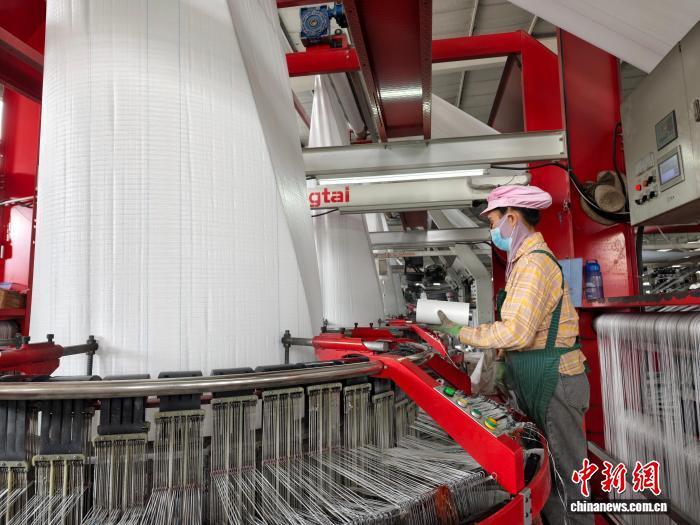 1月13日，儋州伟达化工有限公司生产车间内，工人正利用上游企业生产的聚乙烯开展再加工，制作集装吨袋。　 中新社记者 　王子谦 　摄