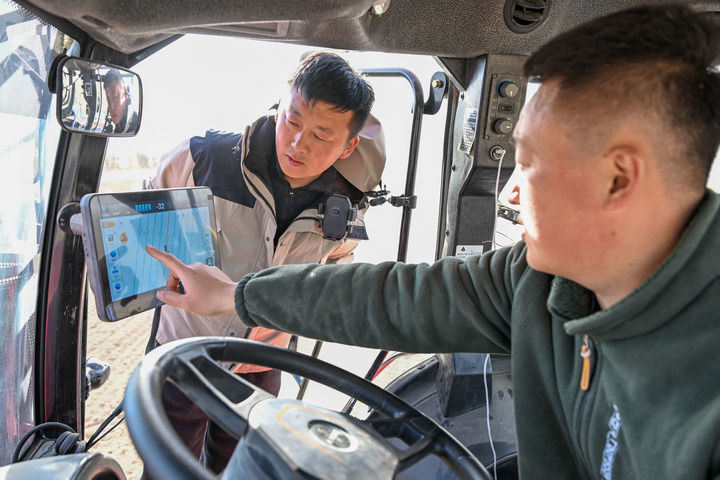 2026年3月24日，在新疆伊犁哈萨克自治州察布查尔锡伯自治县孙扎齐牛录镇，罗俊杰（左）和农机手查看北斗自动导航系统确定播种地块。新华社记者 丁磊 摄