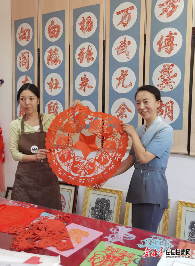 陈志（右）展示剪纸作品
