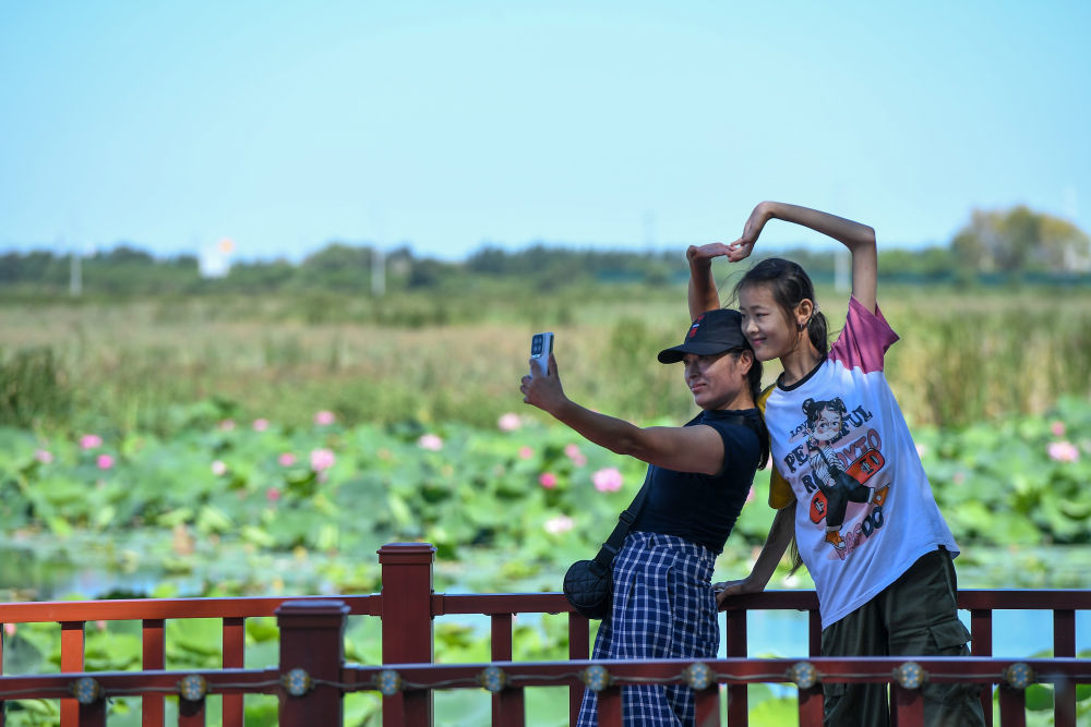 2024年8月26日，游客在查干湖拍照留念。参考冬捕节的成功经验，当地在春、夏、秋季分别举办捺钵开湖节、圣湖荷花节、湿地观鸟节等节庆活动，打造“四季的查干湖”。