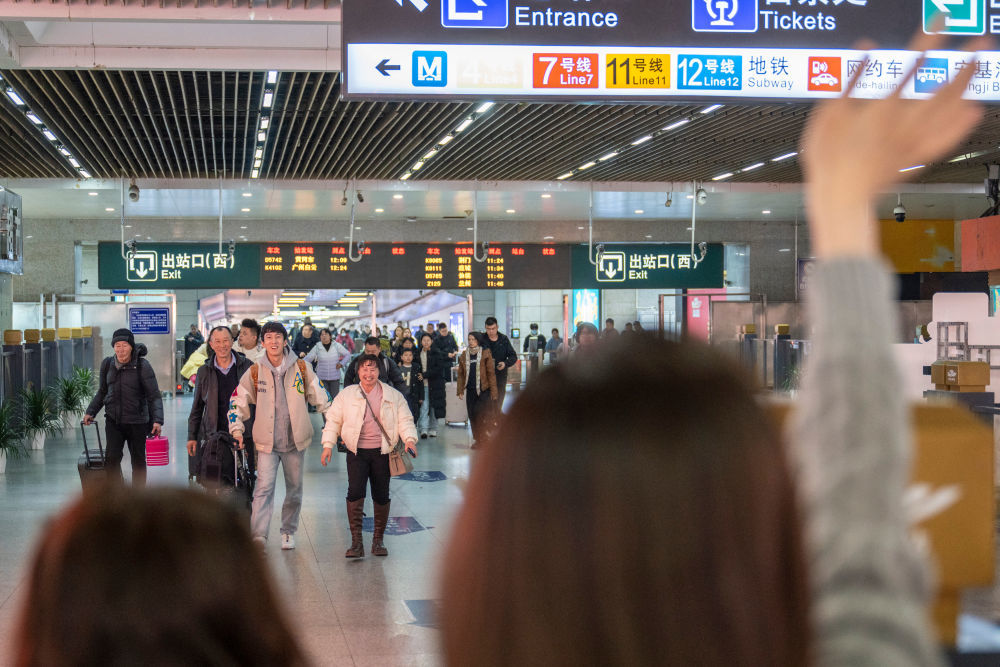 2026年2月14日,在湖北武昌站,王女士(前)向走出出站口的家人挥手。王女士2016年来武汉上学,2022年留武汉工作。今年王女士的父母和弟弟第一次从吉林珲春来武汉过年。新华社记者 伍志尊 摄