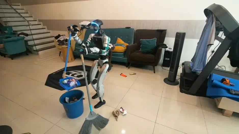 图注：G1 在真实家庭客厅里执行清洁任务，这类带家具、杂物和动线的场景正是全身遥操作数据要覆盖的对象。