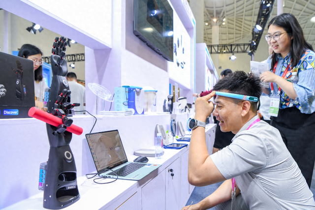 第六届消博会智能产品及外贸优品展区内，参展人员在了解脑科学人工智能设备。苏弼坤 摄