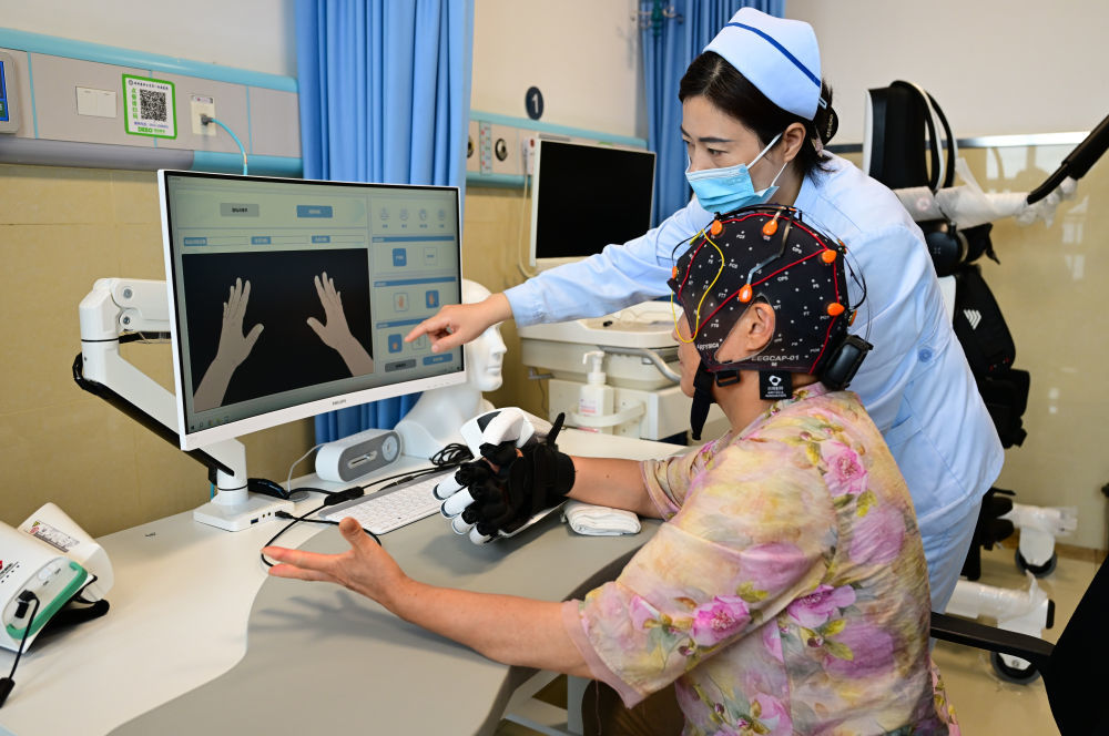 2026年7月17日，在位于安徽省蚌埠市的蚌埠医科大学第一附属医院脑机接口与神经调控病房，医务人员指导一名患者用无创脑机接口设备进行手部康复训练。新华社记者 周牧 摄