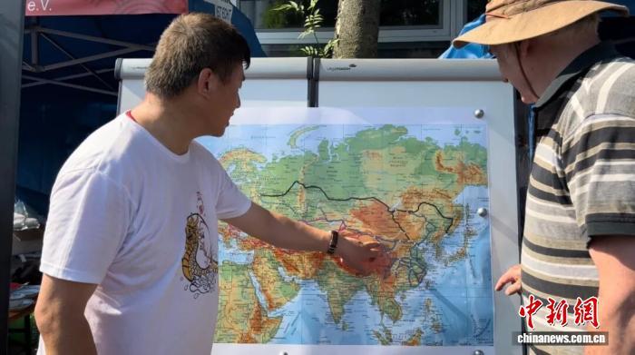 2023年6月11日，德国民众沃尔夫冈&middot;卡利施克在德国杜伊斯堡趣味龙舟赛上了解中欧班列线路图。中新社记者 马秀秀 摄