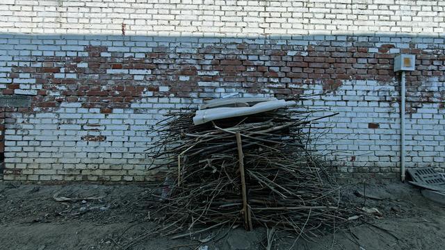 老人将捡来的柴火堆放在门外