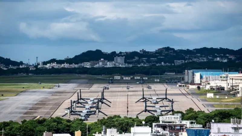 驻日美军普天间基地内,多架“鱼鹰”运输机停在跑道上,周边紧邻居民区与城市建筑。(图源:BBC网站)