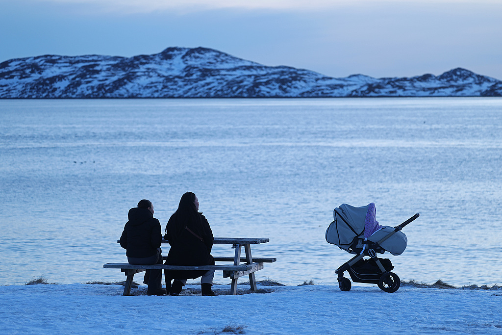 当地时间2026年1月25日,格陵兰岛努克,人们带着婴儿车坐在被白雪覆盖的海滩上。视觉中国 图