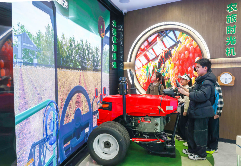 ↑4月2日，在江苏省江都现代农业产业园，孩子们模拟驾驶拖拉机。新华社发（任飞摄）