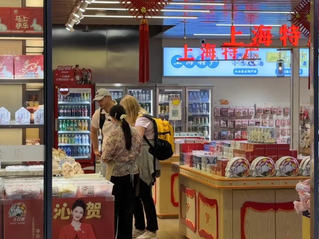 国庆假期，外国游客在上海虹桥火车站内购买上海特产。新华社发（陈晨 摄）