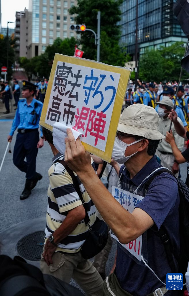 8月15日，在日本东京的淡路公园内，日本民众手持标语参加示威游行。新华社记者 贾浩成 摄