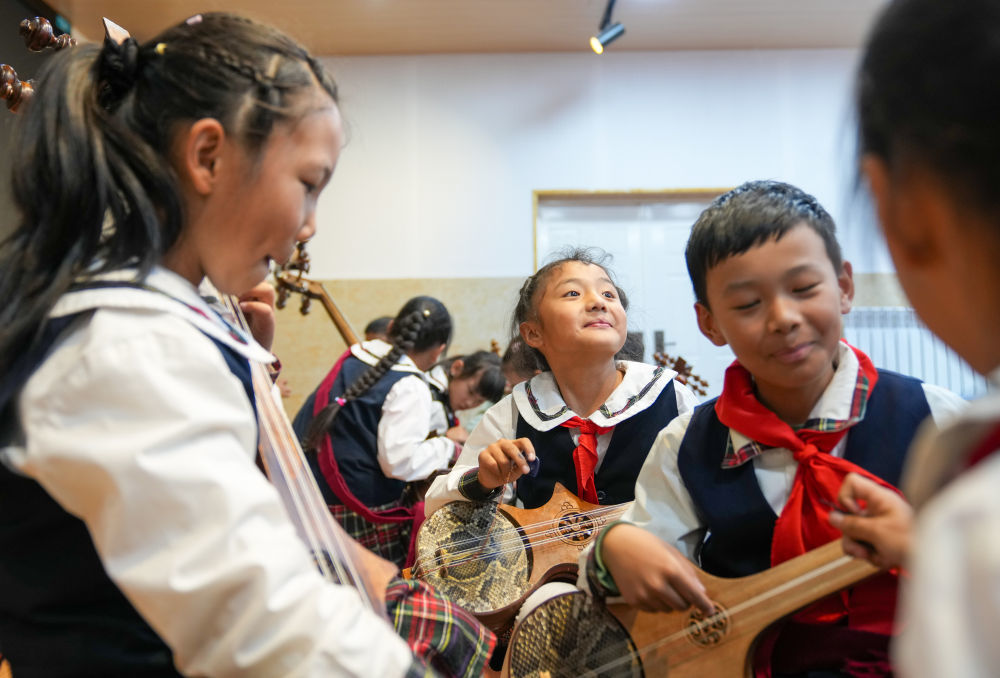 2025年9月11日，在西藏拉萨市实验小学，孩子们在弹奏扎念琴间隙休息。2014年，“扎念琴制作技艺”入选第四批国家级非物质文化遗产代表性项目名录。