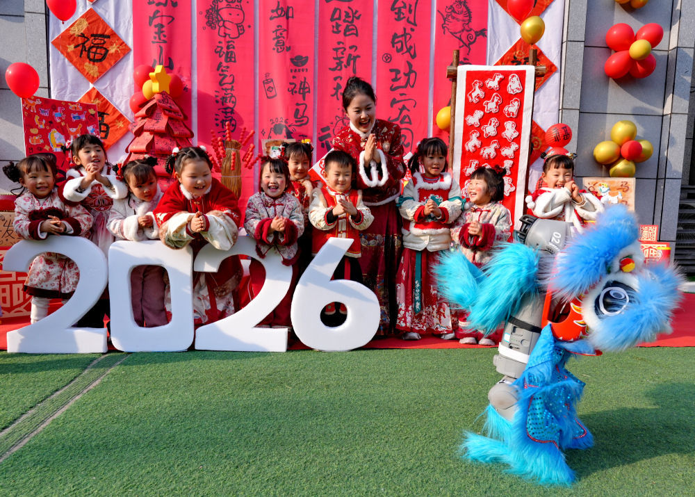 2026年1月14日,在四川省遂宁市高新区瑰宝明珠幼儿园举办的迎新春非遗庙会上,孩子们和身披舞狮服的机器狗互动。新华社发(钟敏 摄)