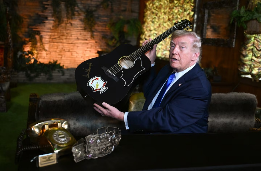 特朗普在参观“雅园”时用一支金色记号笔在一把“猫王”吉他复制品上签名。图源：外媒