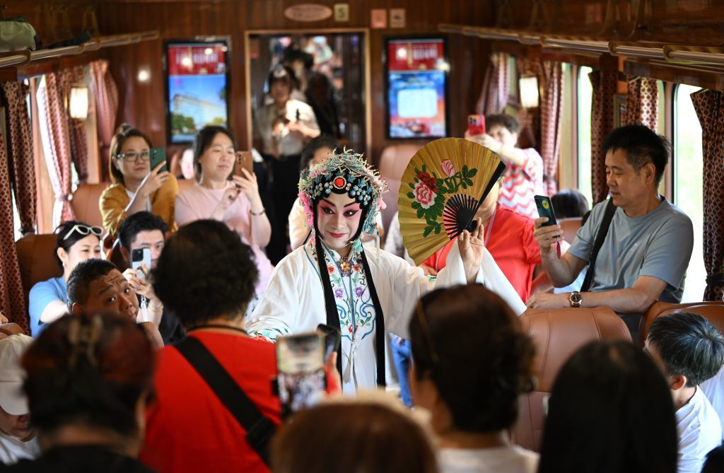 7月29日，在主题娱乐沉浸式文旅专列“津旅时光号”复古客座车厢，旅客观看戏曲表演。新华社记者 孙凡越 摄
