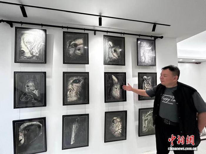 图为台胞李永星介绍自己创作的十二生肖画作。　中新网记者 符宇群 摄
