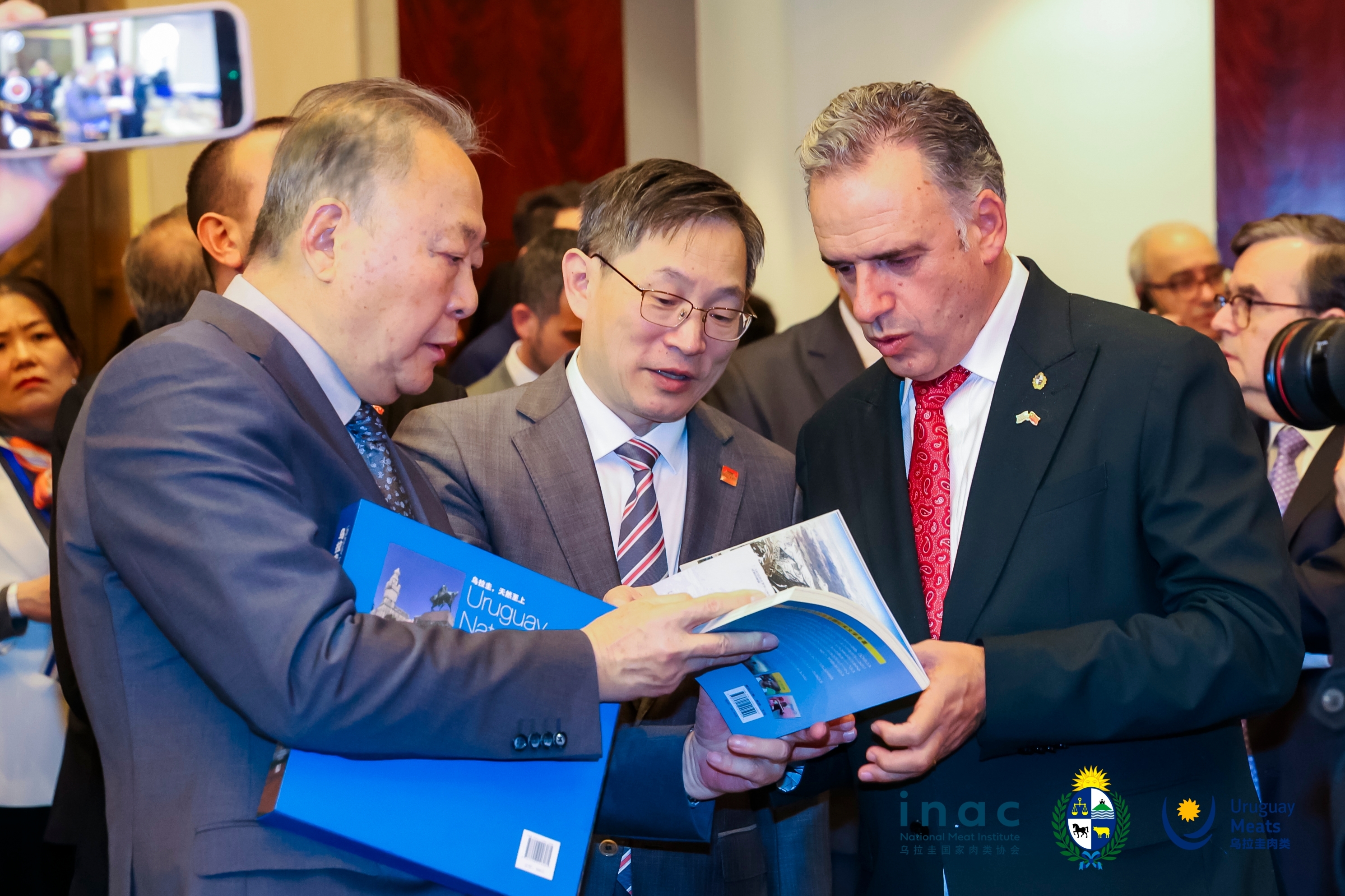 2026年2月6日，余熙(左)受邀出席乌拉圭总统亚曼杜&middot;奥尔西在上海举行的招待会活动。图为中国驻乌拉圭大使黄亚中(中)与乌拉圭总统翻阅两部乌拉圭主题著作。 乌拉圭驻华大使馆供图