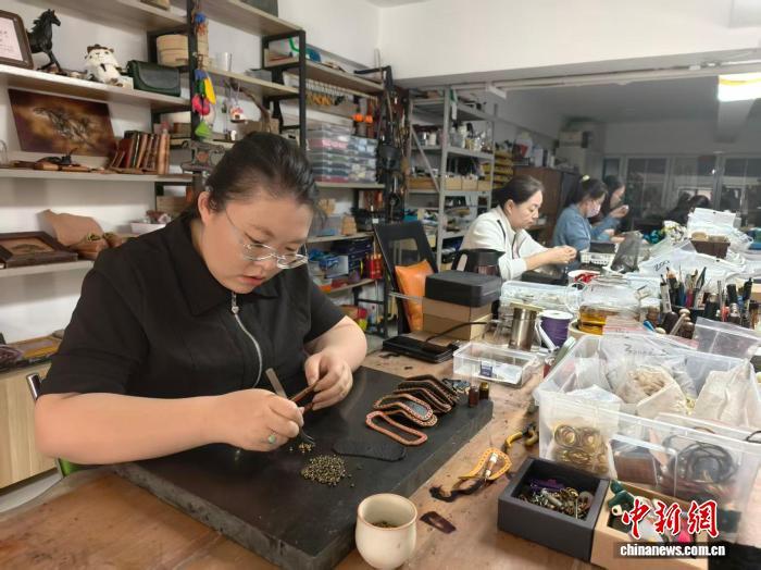 9月21日,内蒙古自治区通辽市经济技术开发区新城街道河畔花园内,当地居民正在制作皮雕产品。中新网记者 勉征 摄