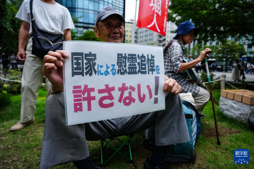 8月15日，在日本东京的淡路公园内，日本民众手持标语参加集会。新华社记者 贾浩成 摄