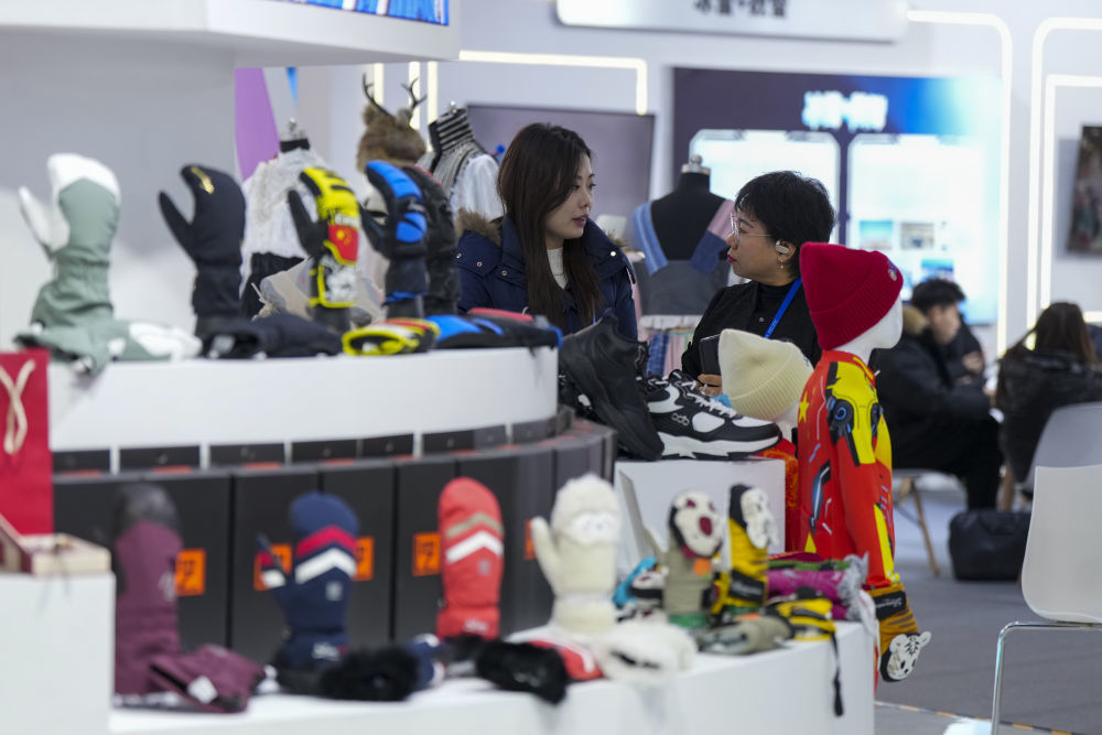 2026年1月6日，在2026哈尔滨国际冰雪经济博览会上，参展企业代表（右）向参观者介绍冬季保暖用品。