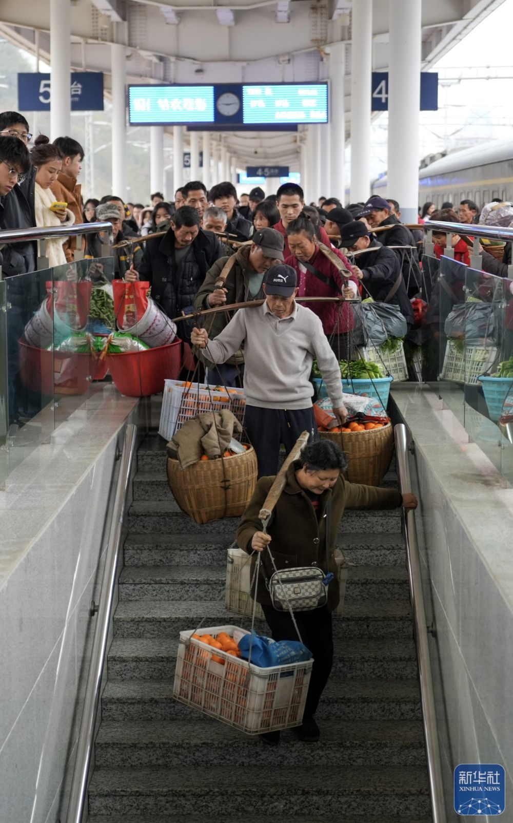 ↑ 2月12日,在贵州省铜仁市铜仁火车站,村民挑着蔬果出站。新华社记者 刘续 摄