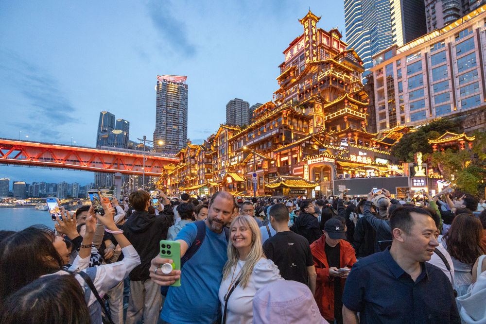 ↑ 4月22日，外籍游客在重庆市渝中区洪崖洞景区前自拍。