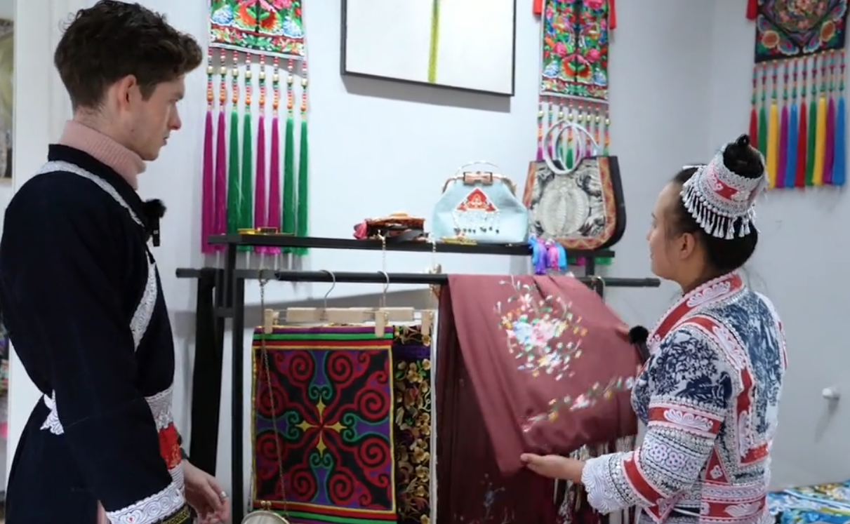 在贵州化屋村,苗族绣娘向英国博主“亚亚亚亚当”介绍苗绣制作