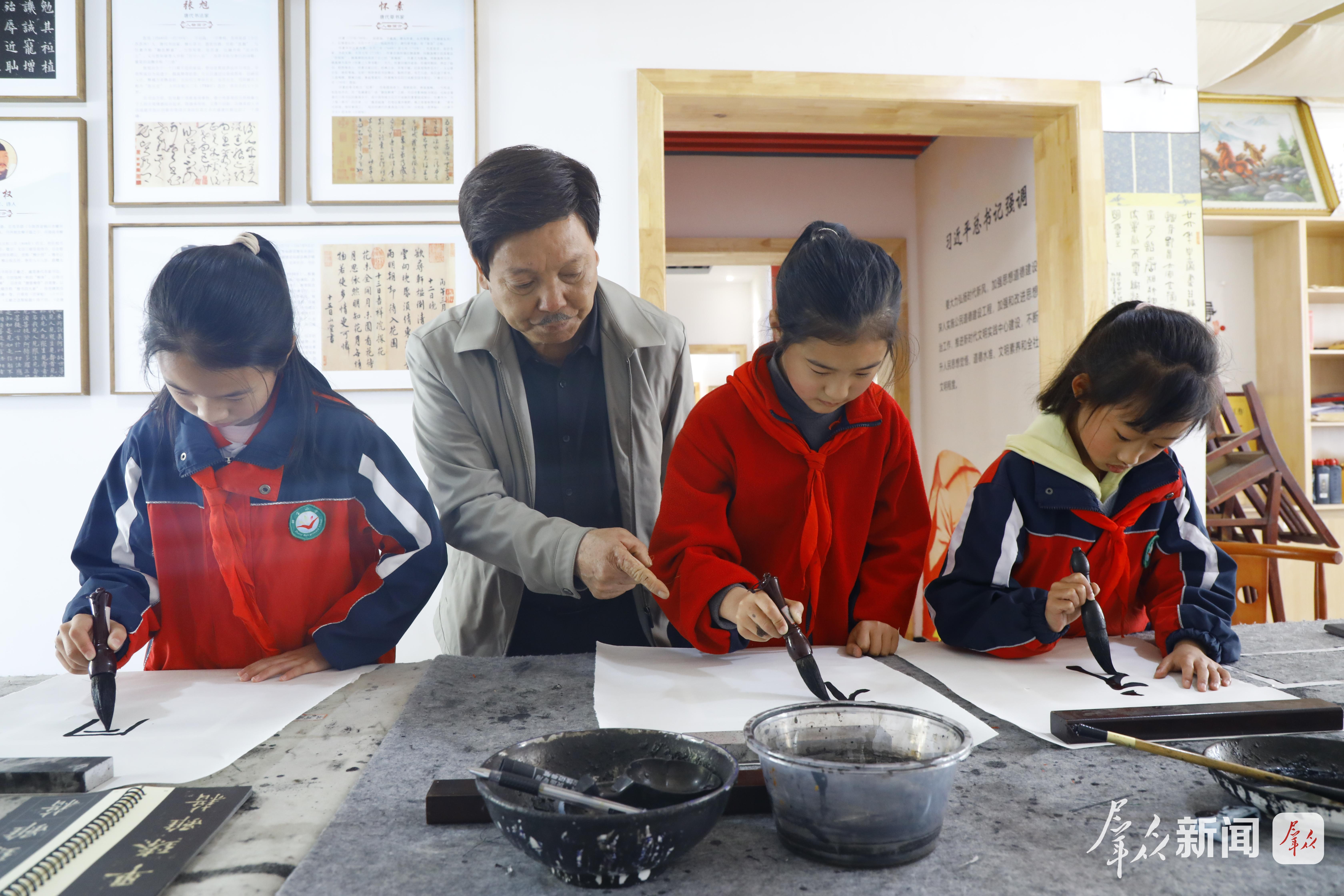 在镇坪县钟宝镇塘坊坝社区，彭长明指导学生练习书法。