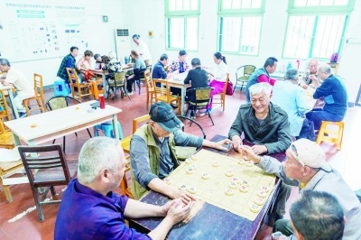 双桥新村社区活动室内，老人们围坐桌边下象棋、休闲交流。 南京日报/紫金山新闻记者 沐剑平 摄