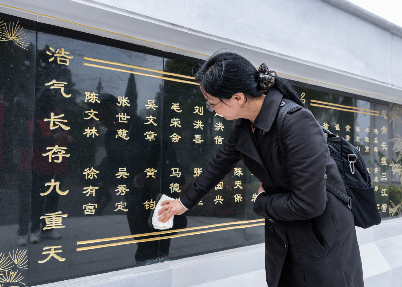 黄钧烈士的孙女黄熊熊擦拭墓碑上爷爷的名字。.jpg