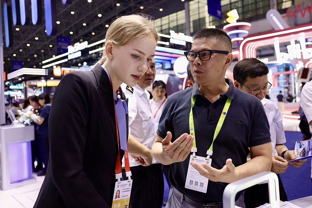 外国观众在科技消费展区了解中国企业生产的人工智能眼镜。（视觉中国）