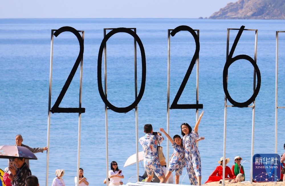 ↑ 1月1日,游客在海南省三亚市大东海旅游区拍照。新华社发(李学仕 摄)