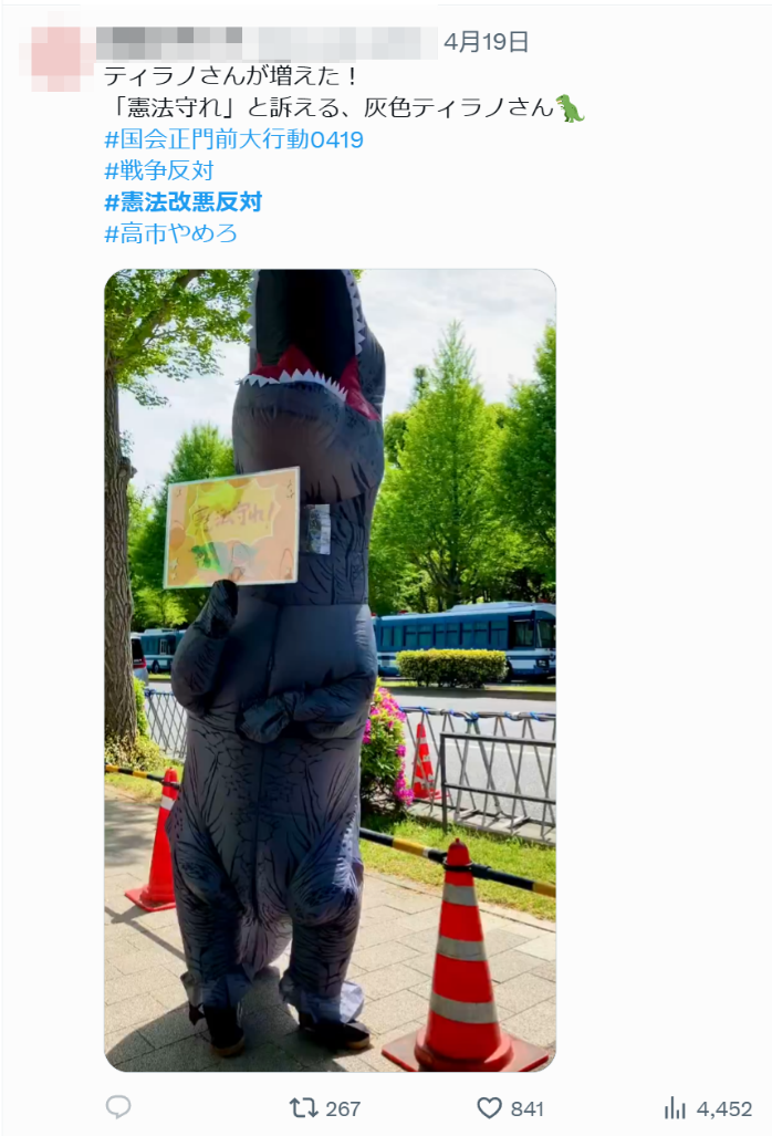 身穿恐龙服的日本民众手举“守护宪法”标语牌