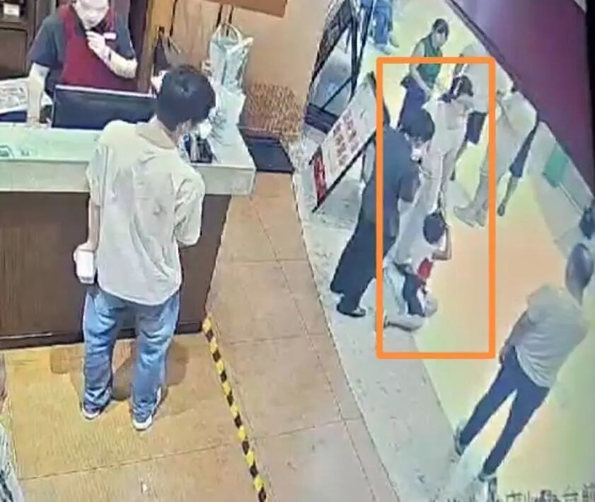 男童被拎着衣领，店员劝解（监控截图）