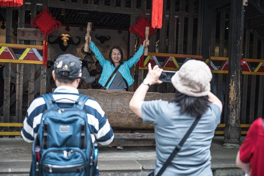 10月19日,游客在腾冲市清水镇三家村中寨司莫拉佤族村体验传统乐器。