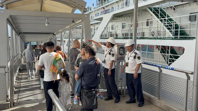 工作人员维持旅客登轮秩序。
