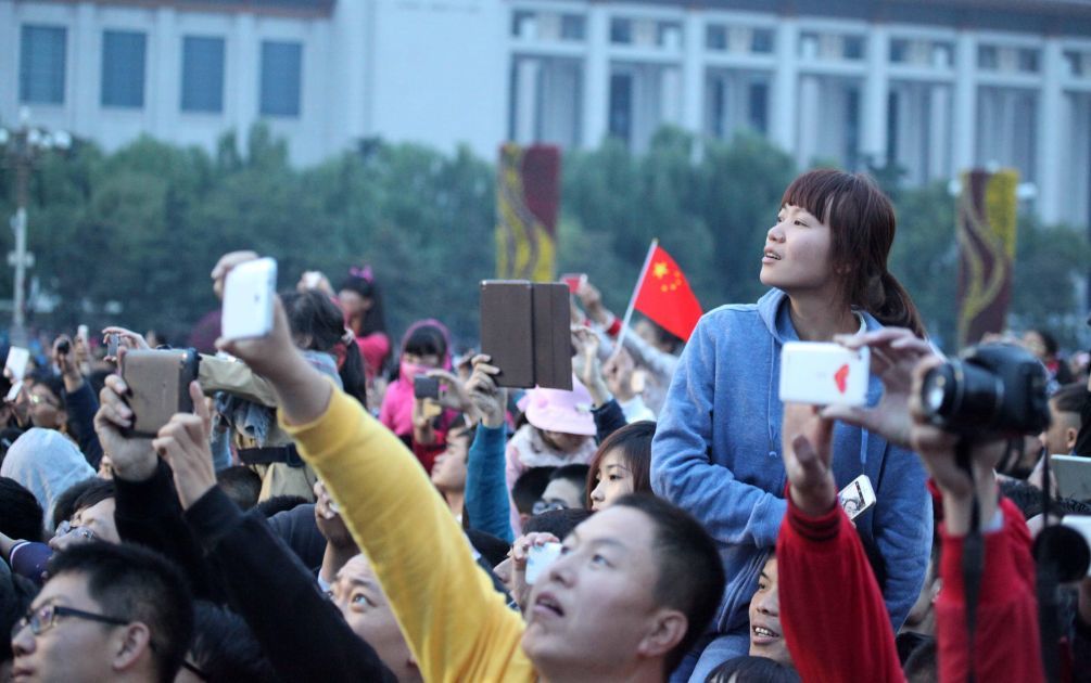 2014年10月1日,人们相聚在天安门广场观看升旗仪式。新华社发