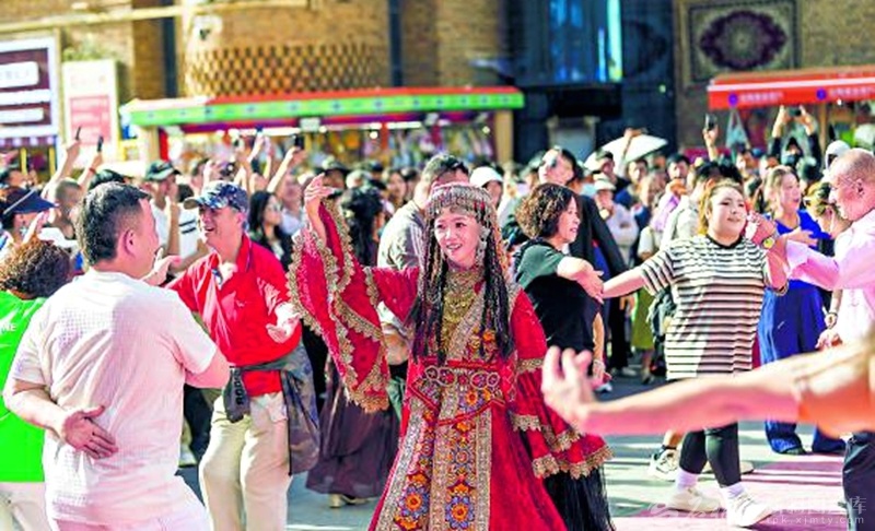 5月27日，新疆国际大巴扎景区游人如织。游客在这里游玩、购物、品尝美食。图为游客伴随音乐跳起欢快的舞蹈。 孙振嵩摄