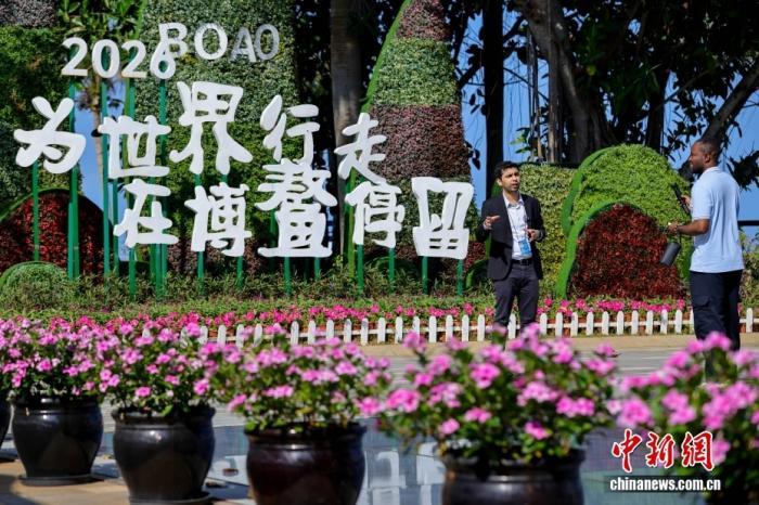 博鳌亚洲论坛2026年年会将于3月24日至27日在海南博鳌举行，外籍媒体记者在新闻中心外的一处户外主题景观前出镜。