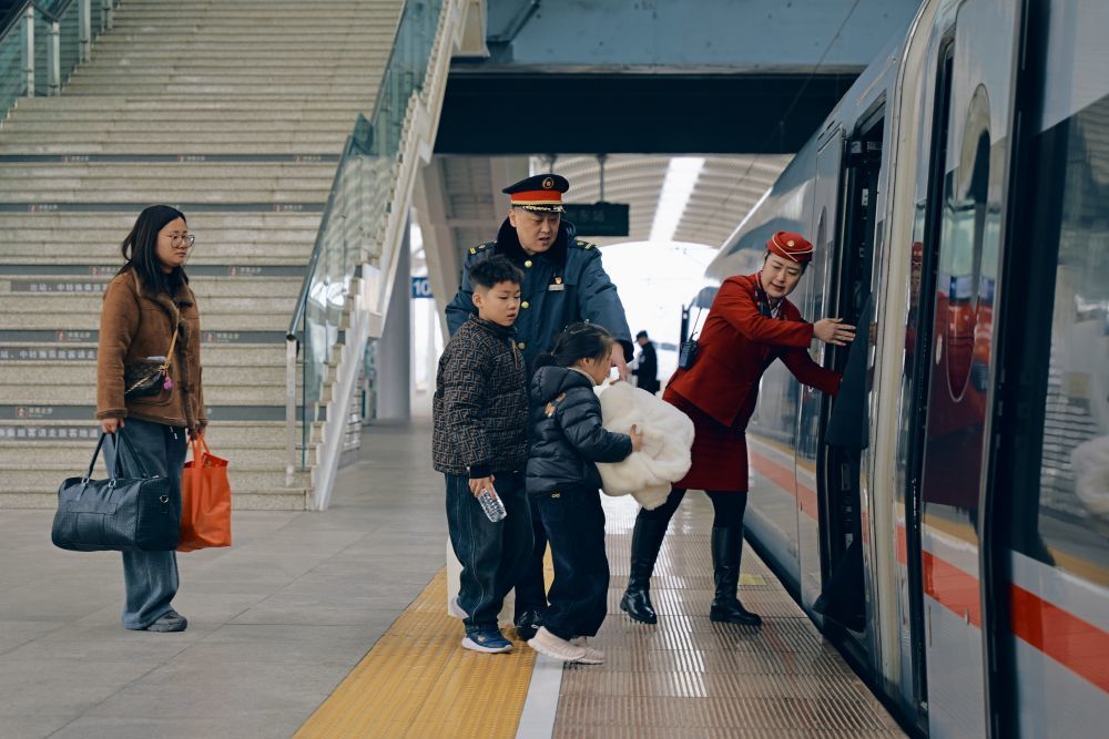 ↑ 2月16日，铁路徐州东站工作人员协助旅客上车。新华社发（张光磊摄）
