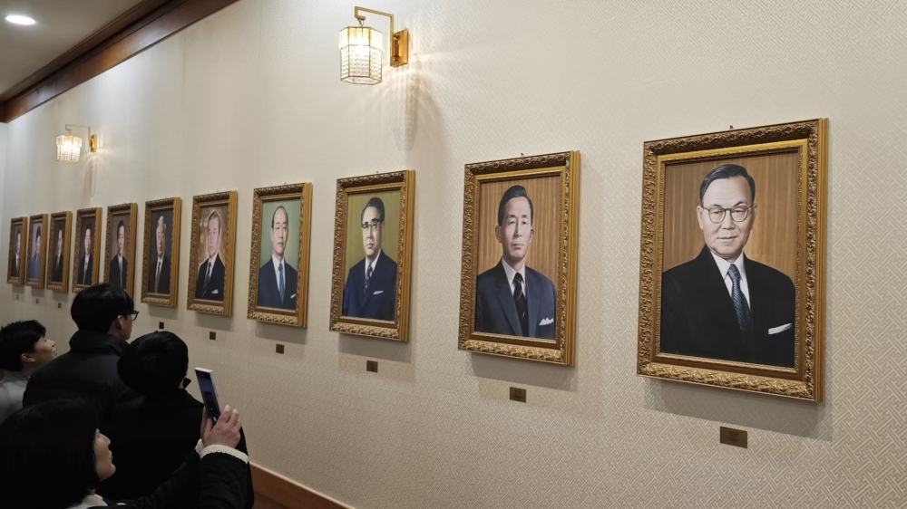 游客在参观青瓦台本馆里的历届韩国总统照片。 参考消息