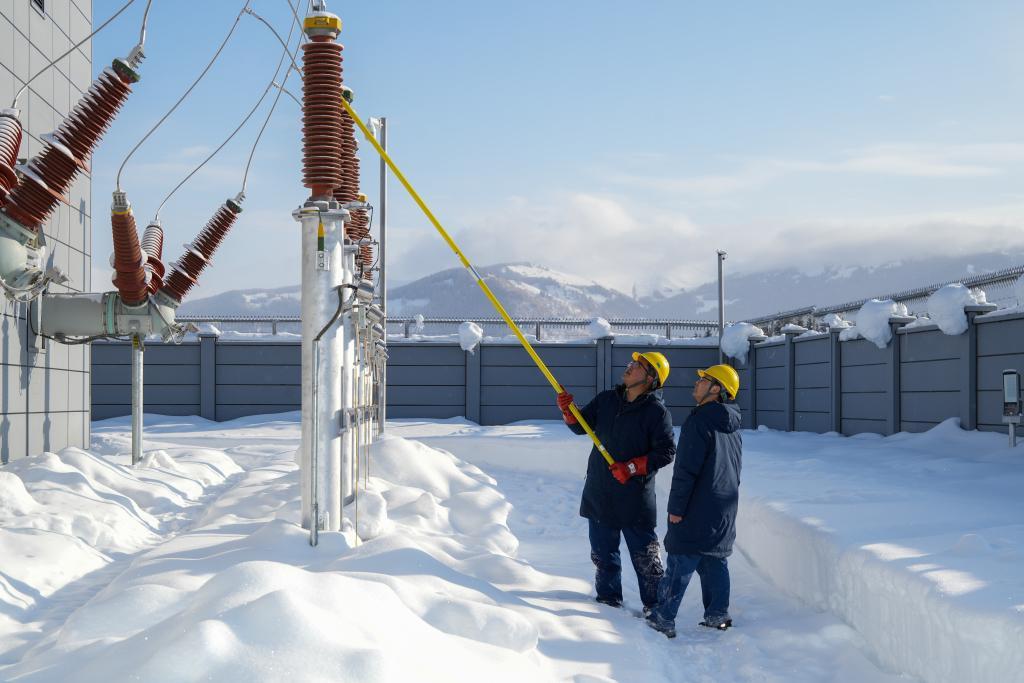 吉克普林110千伏变电站工人贾浩然、包栩闻在清除电力设备积雪。新华社记者徐宏岩 摄
