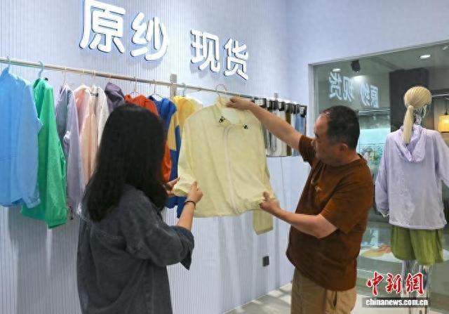 6月初，中国轻纺城阛阓内，布商(右)通过样衣向客商先容原纱防晒面料。项菁 摄