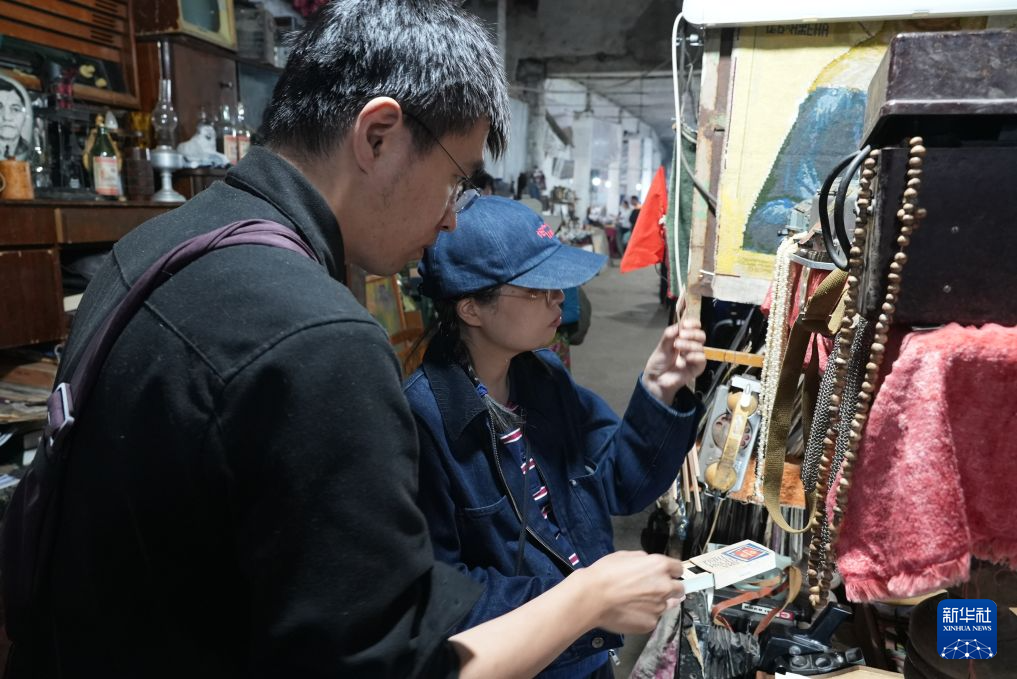 10月3日，在乌兹别克斯坦首都塔什干东郊的扬吉阿巴德跳蚤市场，中国游客在拉希德的摊位选购老物件。新华社发（扎法尔&middot;哈利洛夫摄）