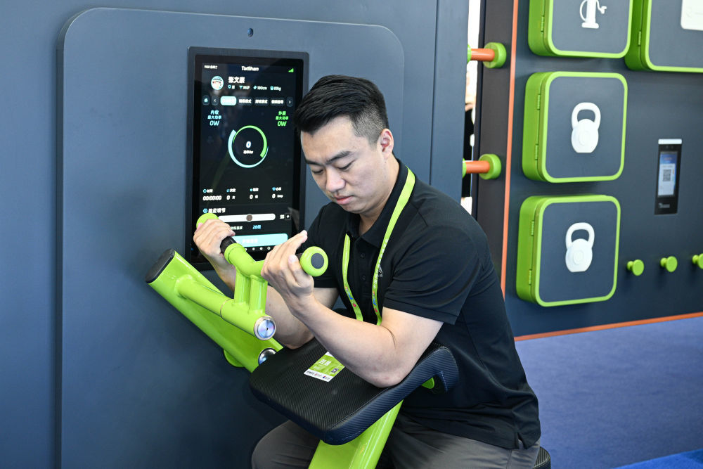 ↑ 4月14日，观众在第六届消博会现场体验智能二三头肌弯举训练器。新华社记者 蒲晓旭 摄