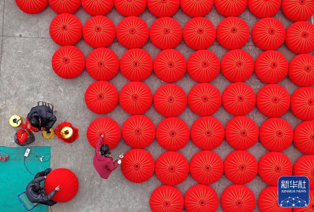 ↑ 1月21日，在浙江省台州市仙居县横溪镇一家灯笼加工作坊，工人赶制大红灯笼（无人机照片）。新华社发（王华斌摄）