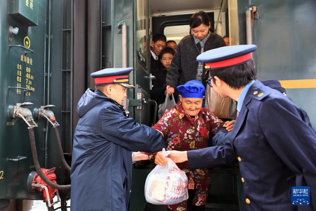 2月25日,在遵义市,5630次列车到达桐梓站后,铁路工作人员协助村民下车。新华社发(王波 摄)